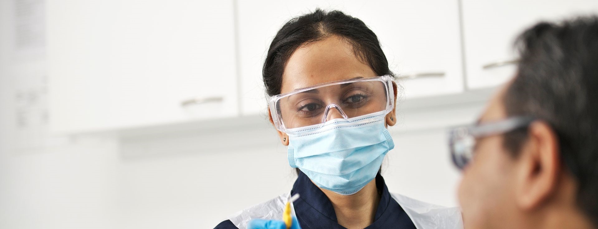 Dentist wearing mask and smiling at patient